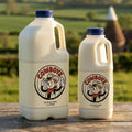 COWBOYZ A2 raw milk 2 litre and 1 litre jugs on a rustic oak table in the Kent countryside