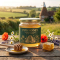 Pips Honey cloudy raw wildflower honey jar with green and gold label, honey dipper, honeycomb and wildflowers on an oak table in Kent