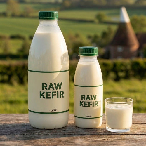 Raw kefir bottles on an oak table with an oast house behind